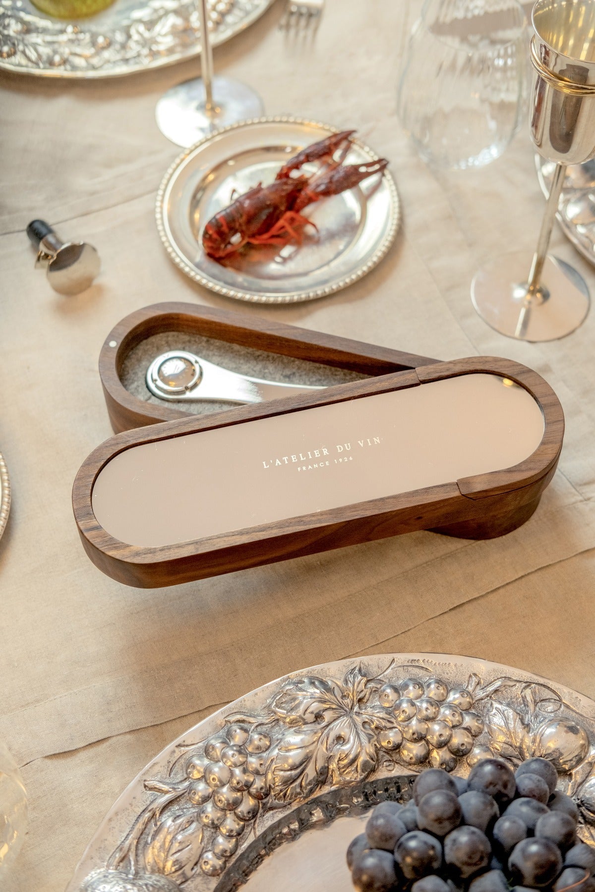 Set Sparkling de L'Atelier du Vin sobre mesa festiva con cubiertos de plata, langostinos y copa de champán