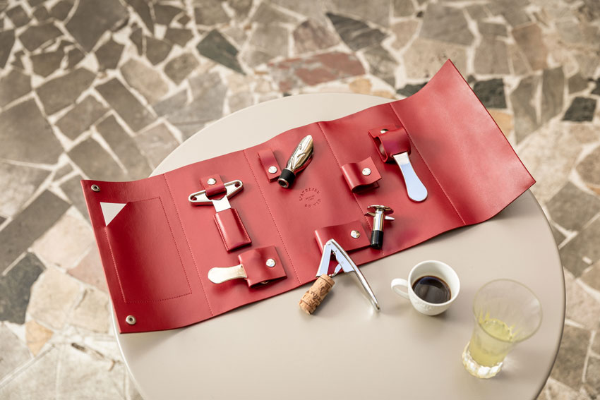 Estuche nómada L'Atelier du Vin Oeno Collection Nomad desplegado en mesa redonda con café y copa de vino blanco