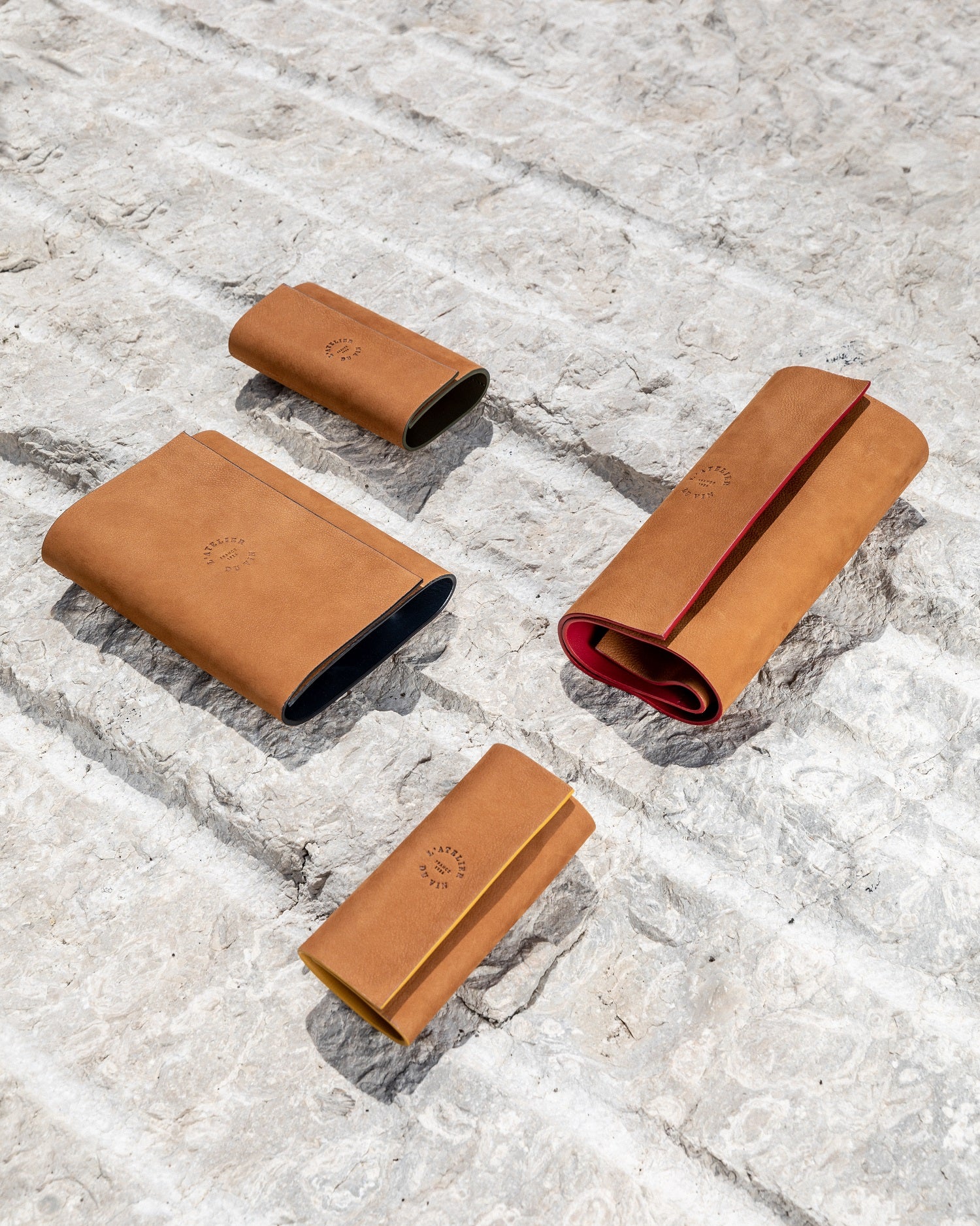 Varios estuches nómadas L'Atelier du Vin Oeno Collection Nomad en cuero natural con distintos colores sobre piedra