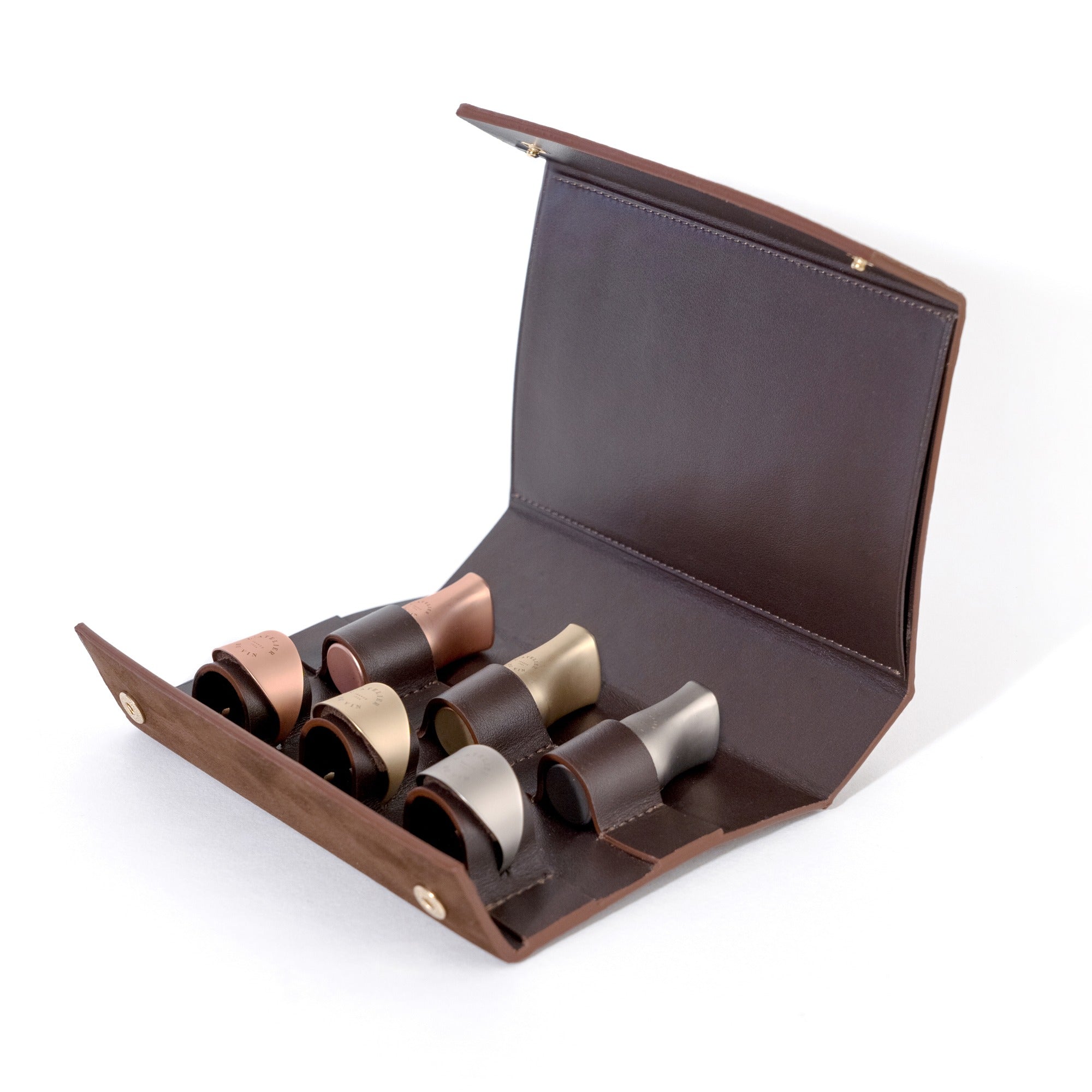 Set Les Bijoux de L'Atelier du Vin abierto con 6 tapones para botellas en cuero y metal sobre fondo blanco