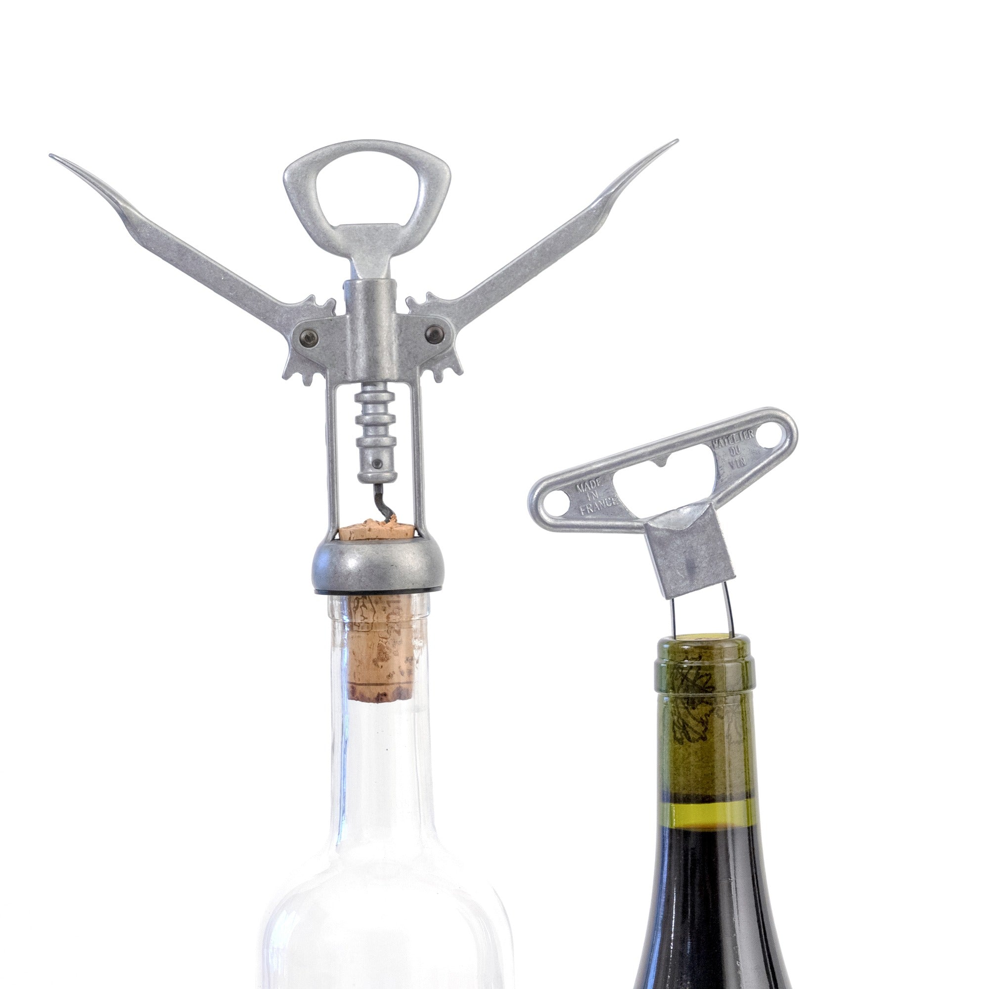 Sacacorchos Les Bons Amis de L'Atelier du Vin insertado en botella de vino blanco junto a abridor en uso