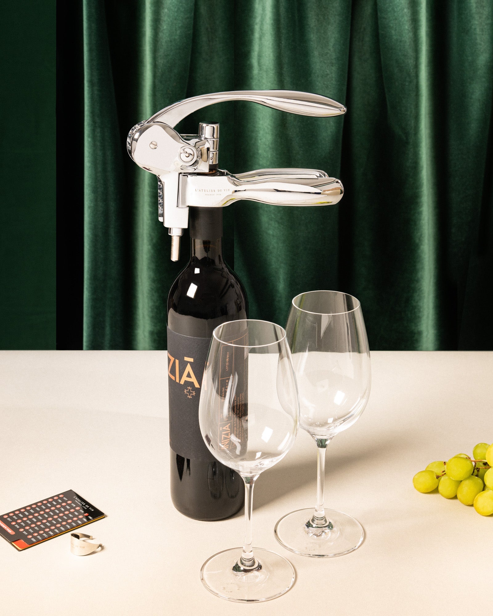 Sacacorchos Oeno Box Sommelier L'Atelier du Vin sobre botella de vino con copas y uvas en ambiente elegante