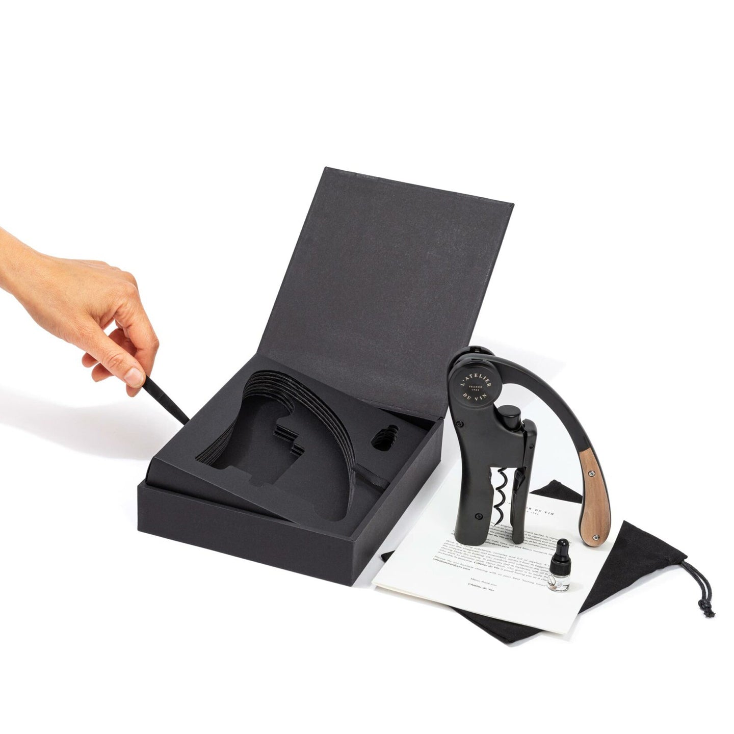 Mano abriendo la caja negra del Oeno Motion Wood & Black L'Atelier du Vin con sacacorchos y accesorios