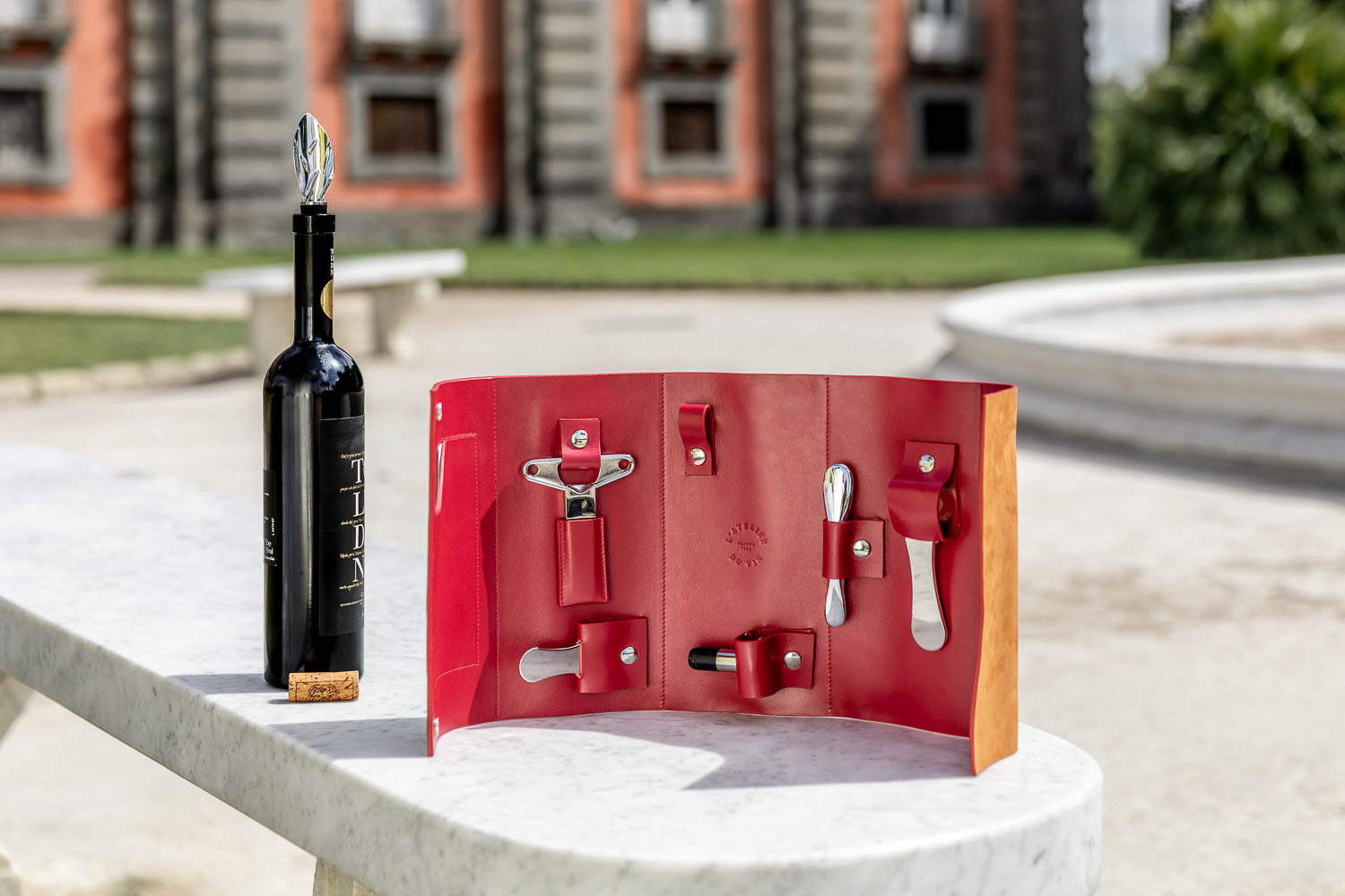 Estuche nómada L'Atelier du Vin Oeno Collection Nomad abierto al aire libre junto a botella de vino en Nápoles