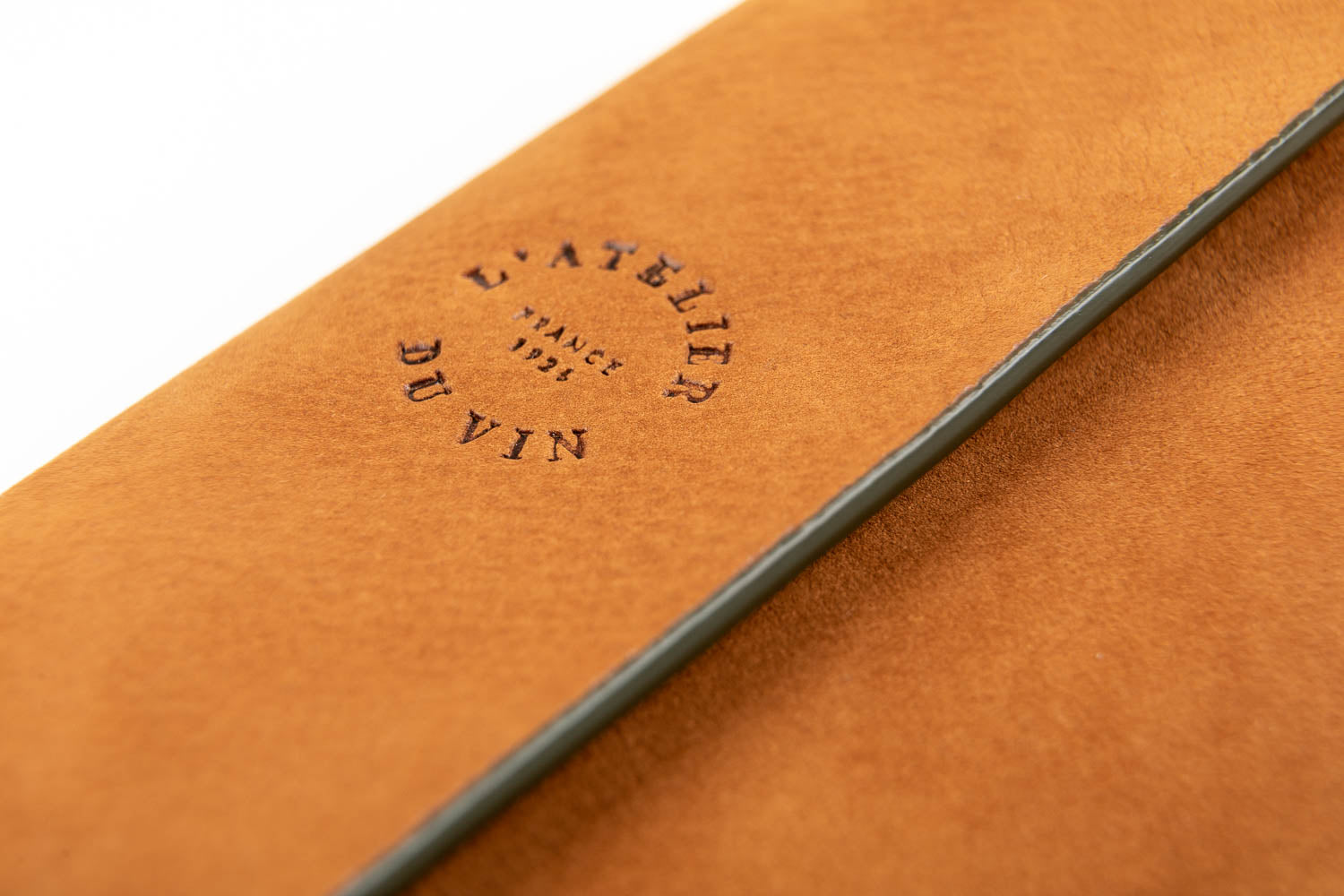 Detalle del logo L'Atelier du Vin grabado en el cuero marrón claro del estuche Bilame Nomad
