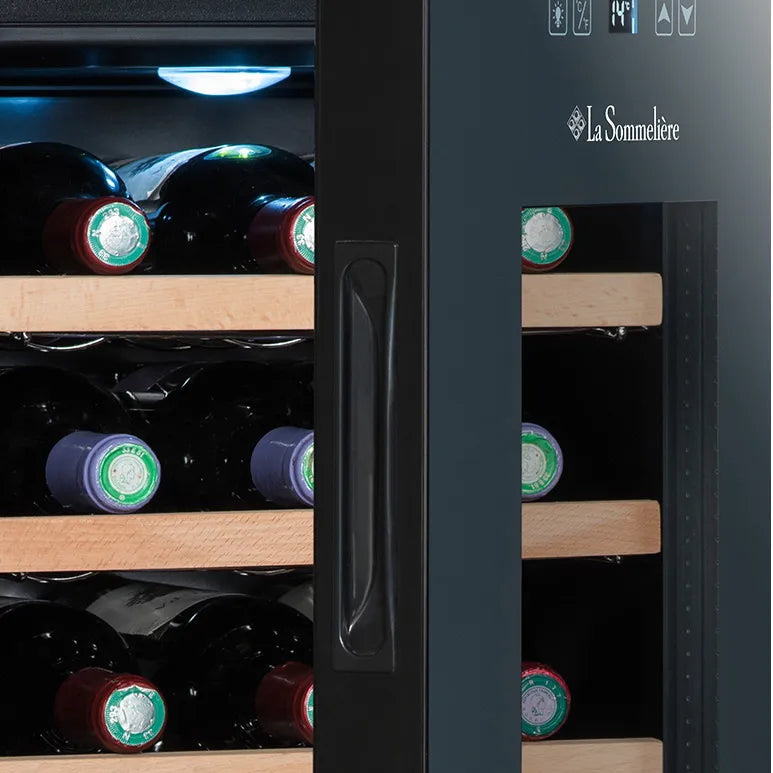 Detalle del lateral frontal de la vinoteca La Sommelière 28SILENCE, mostrando el tirador negro, control táctil superior, luz LED interior y botellas almacenadas en estantes de madera.