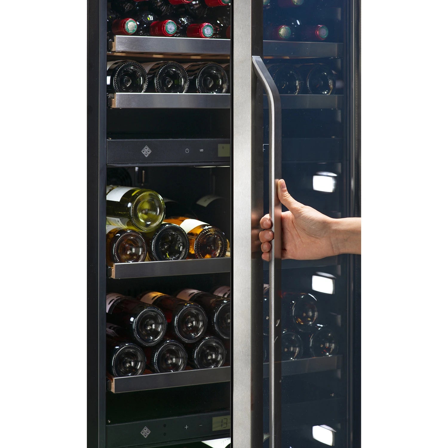 Primer plano de una mano abriendo la puerta de vidrio de la vinoteca La Sommelière MT150DZ. Se observan estantes metálicos con botellas de vino tinto y blanco, iluminación LED en el interior y paneles de control digital visibles entre zonas.