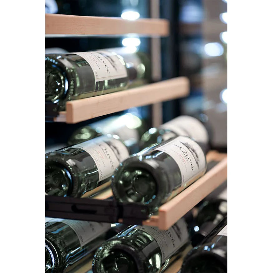 Primer plano del interior de la vinoteca mQuvée, mostrando botellas de vino blanco almacenadas horizontalmente sobre estantes de madera deslizables, con iluminación LED tenue al fondo.