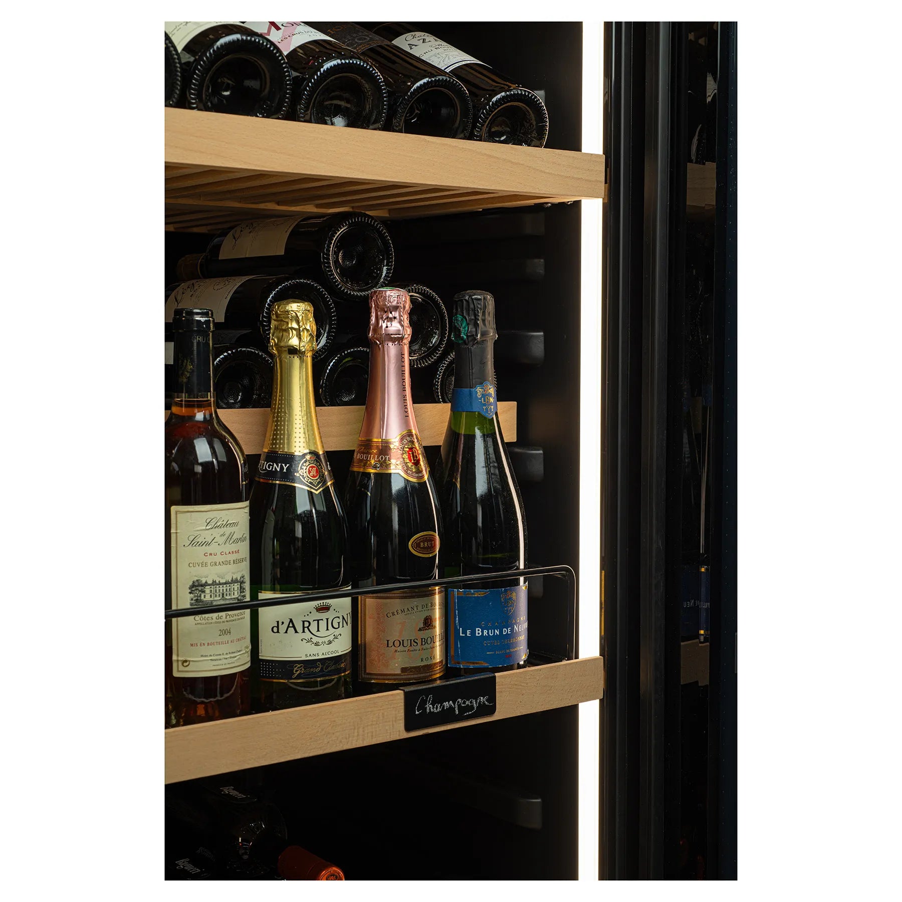 Primer plano de botellas de vino y champán en estante de madera dentro de vinoteca, con iluminación interior cálida y etiquetas visibles.