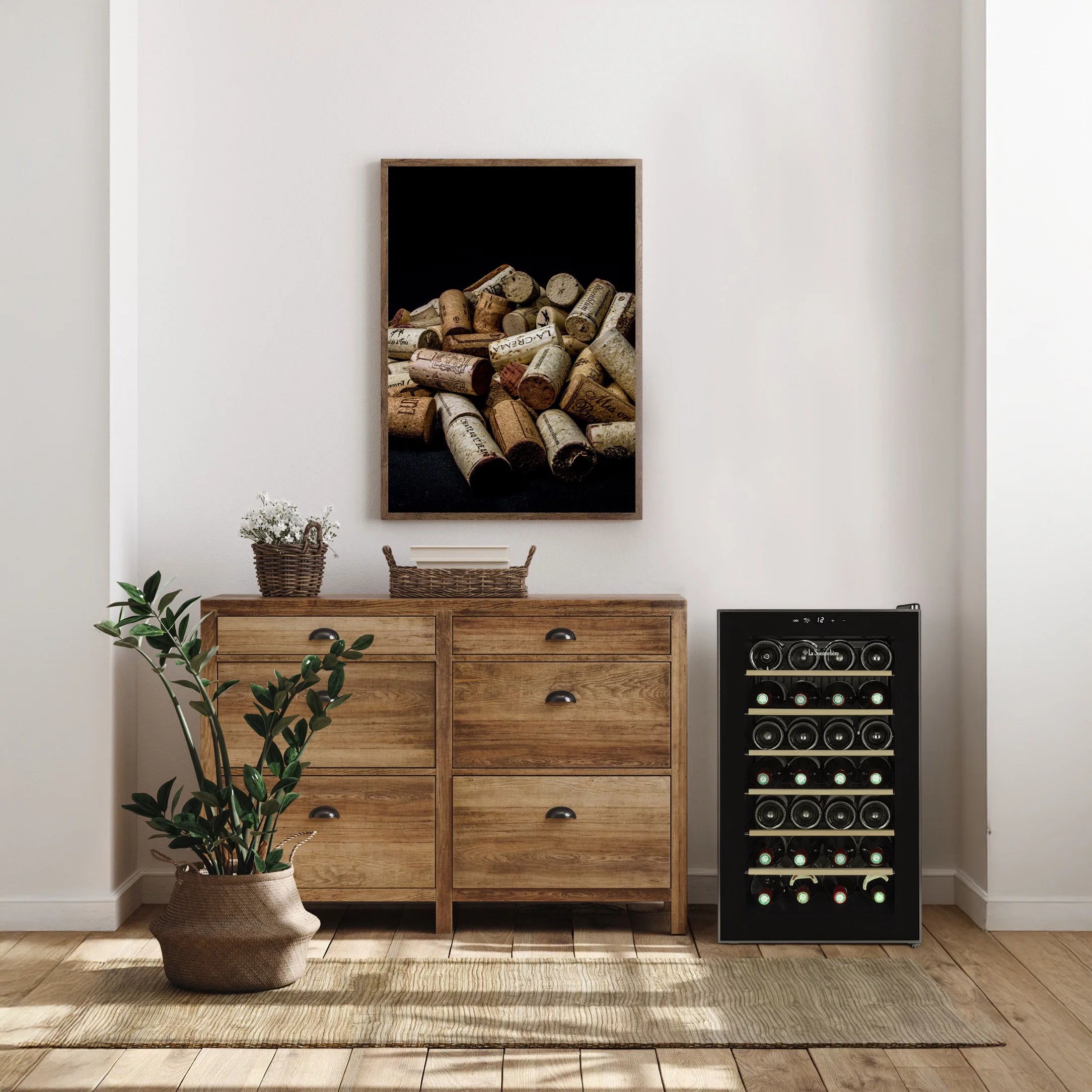 Vinoteca La Sommelière 28SILENCE colocada junto a un mueble de madera en una sala luminosa, decorada con una planta, cestas y un cuadro de corchos de vino.