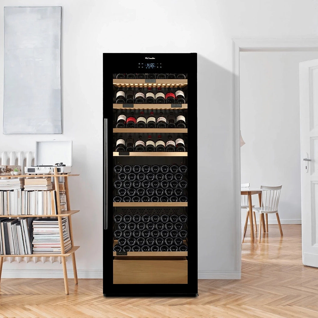Vinoteca La Sommelière VIP306 EDITION llena de botellas en un salón luminoso junto a una estantería