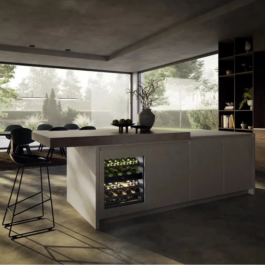 Cocina moderna con isla central que incorpora una vinoteca empotrada Liebherr UWpri 3662 iluminada, con botellas de vino visibles en su interior.