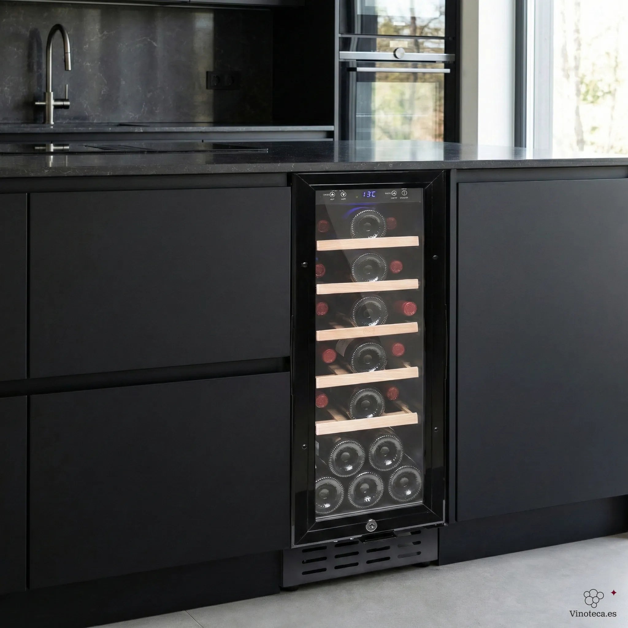 Vinoteca encastrable negra instalada bajo encimera en cocina moderna, con puerta de vidrio, estantes de madera y botellas de vino visibles en posición horizontal.