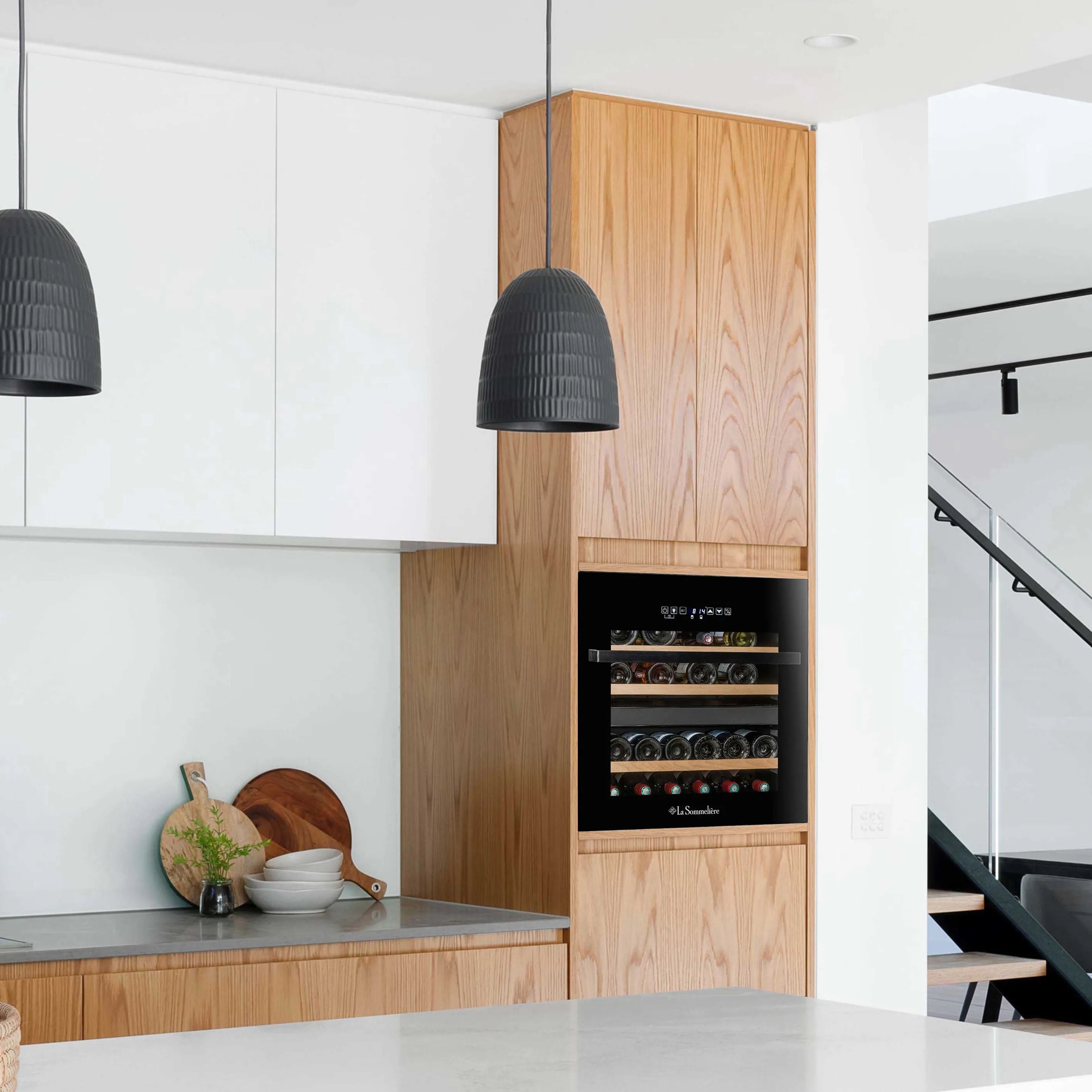 Vinoteca 36 botellas La Sommelière LSBI36BDZ doble zona instalada en una cocina elegante, con estantes de madera llenos de botellas.