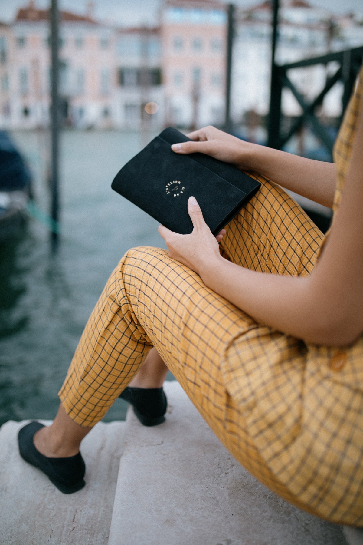 Persona sosteniendo el estuche Oeno Motion Gold Nomad L'Atelier du Vin junto al Gran Canal de Venecia