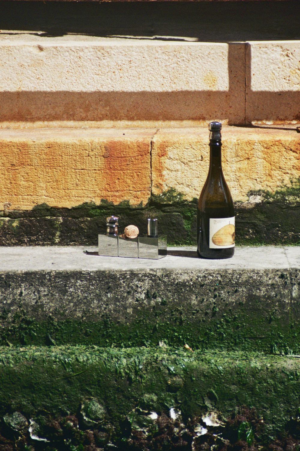 Botella de vino con set de tapones L'Atelier du Vin Bouchons Millésimes sobre escalón de piedra exterior