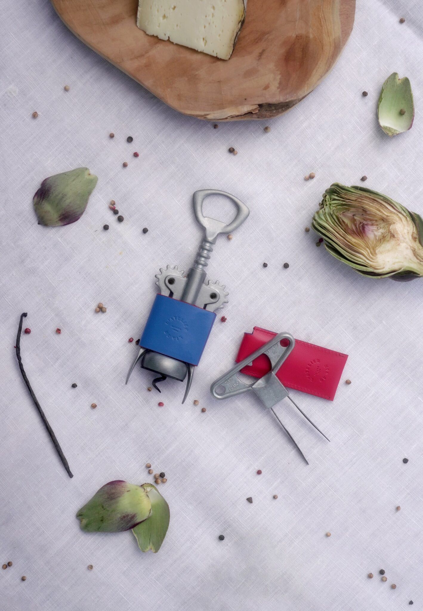 Set Les Bons Amis de L'Atelier du Vin con sacacorchos y bilame en composición de mesa con alcachofas y queso