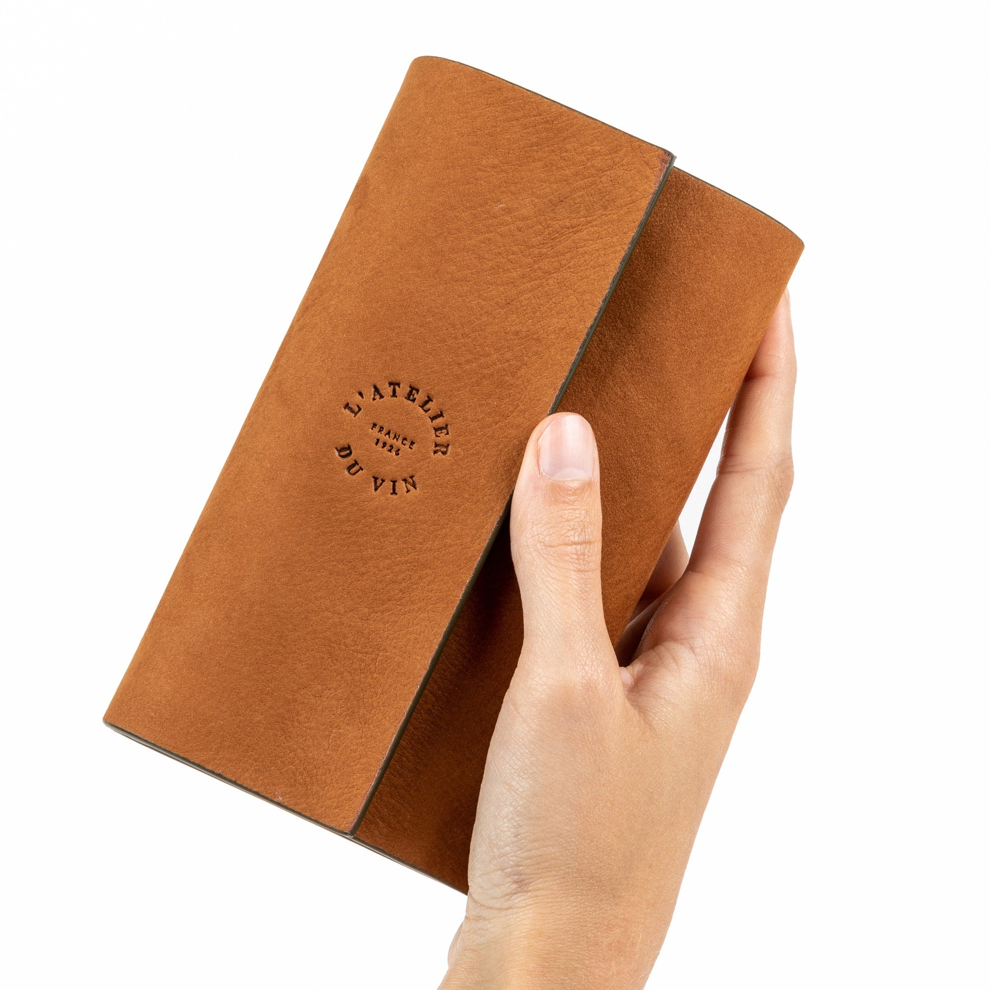 Mano sosteniendo el estuche Bilame Nomad de L'Atelier du Vin cerrado en cuero marrón claro