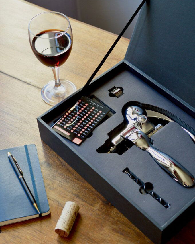 Set Oeno Box Sommelier de L'Atelier du Vin abierto en mesa con copa de vino rojo y libreta azul