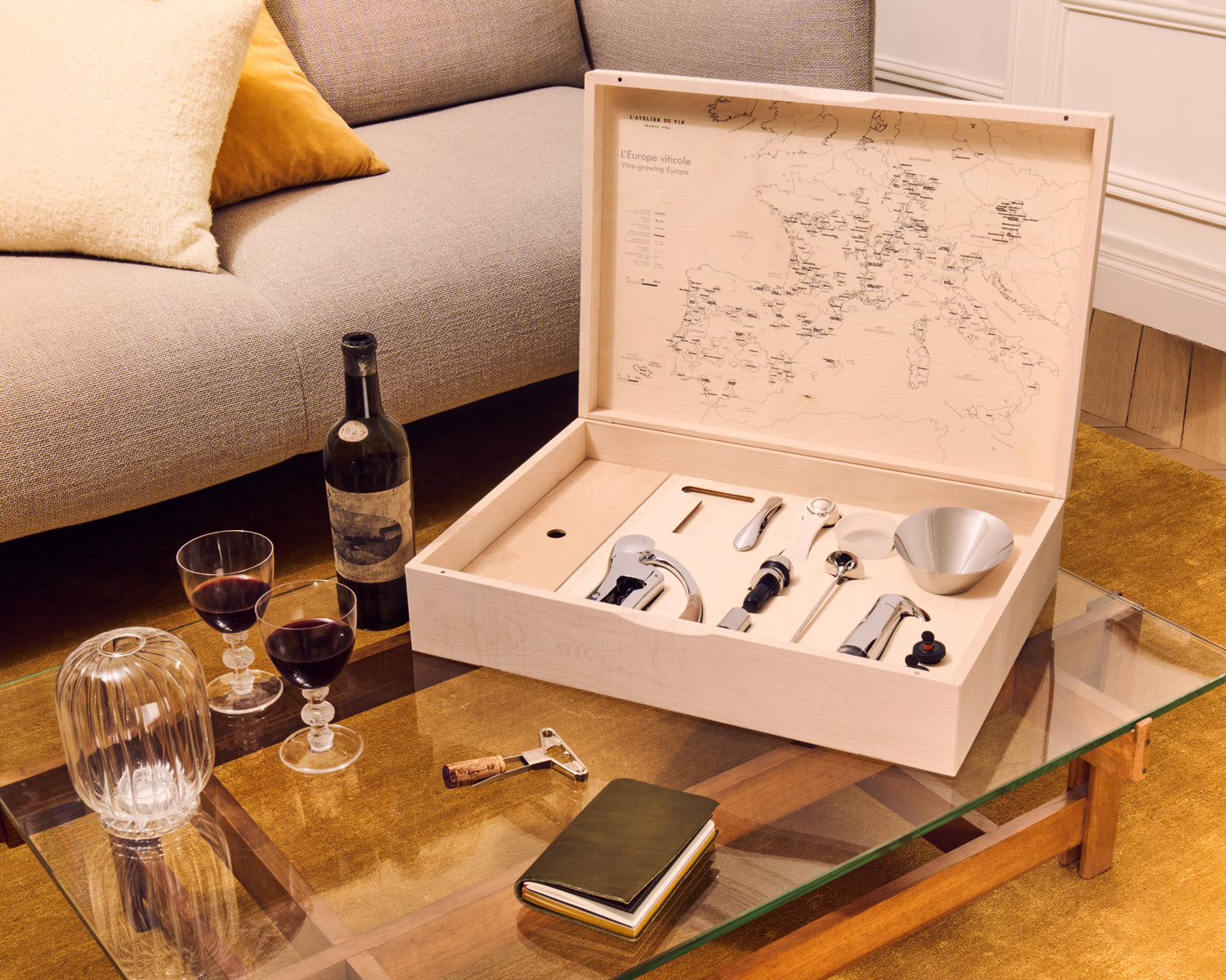 Set L'Atelier du Vin Oeno Box Connoisseur 1 abierto en mesa de salón con copas y botella de vino tinto