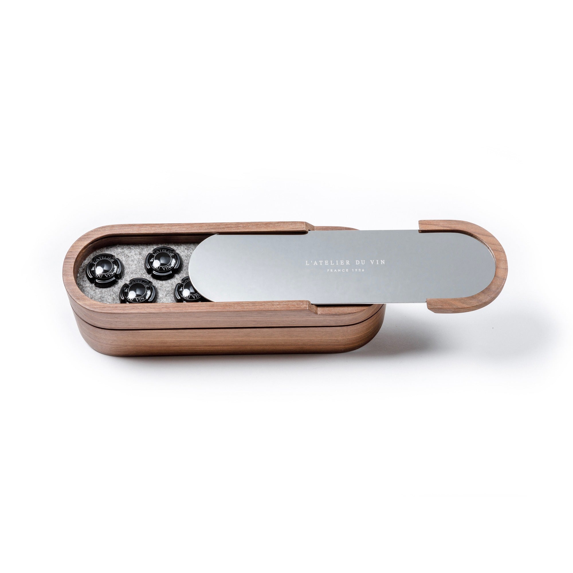 Set Sparkling de L'Atelier du Vin con estuche de nogal entreabierto mostrando tapones para espumosos en acero