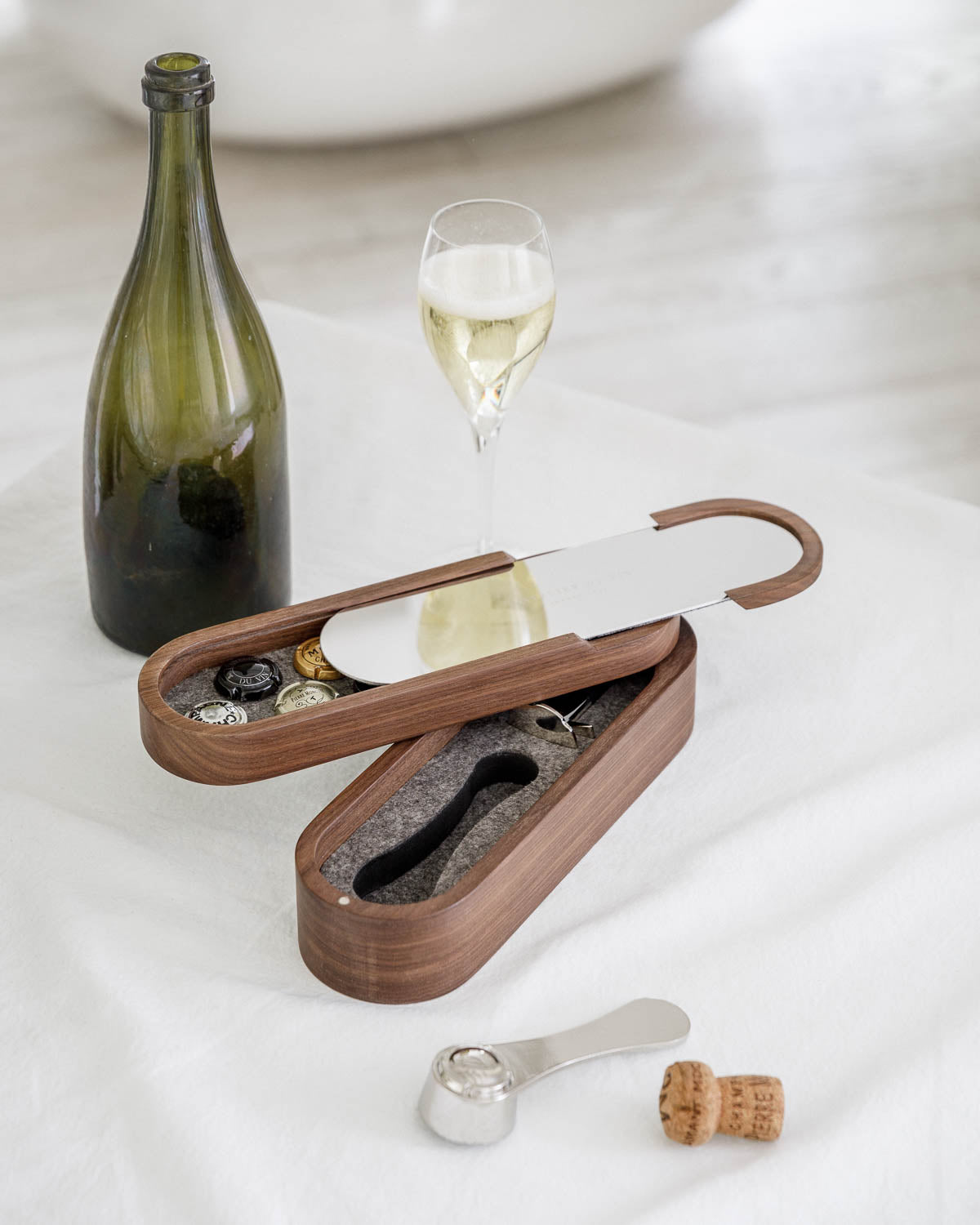 Set Sparkling de L'Atelier du Vin en estuche de nogal abierto junto a botella y copa de champán en composición