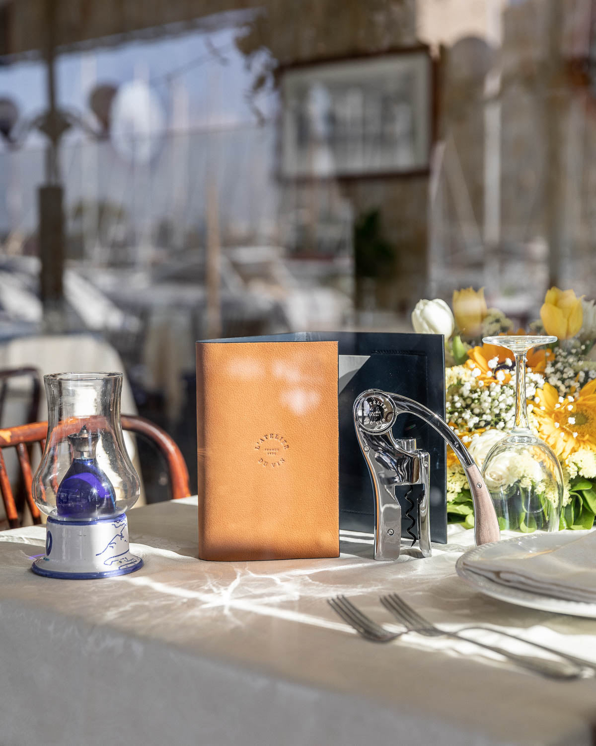 Estuche L'Atelier du Vin Oeno Motion Nomad en mesa de restaurante con descorchador y copas de vino
