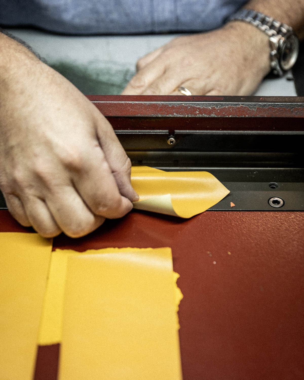 Artesano cortando cuero amarillo en taller para fabricar el estuche Soft Machine Nomad L'Atelier du Vin