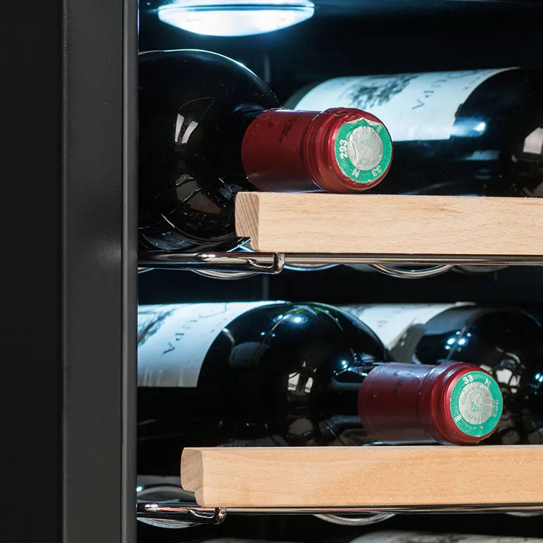 Detalle interior de la vinoteca La Sommelière 28SILENCE mostrando botellas de vino acostadas en estantes de madera, con iluminación LED blanca en la parte superior.