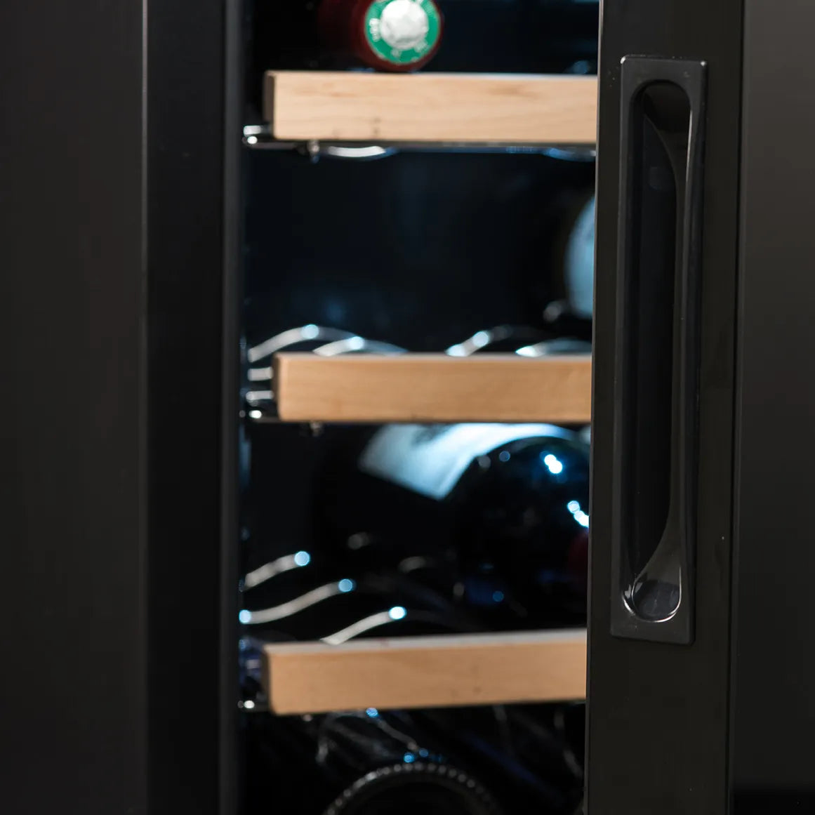 Detalle del lateral de la vinoteca La Sommelière 28SILENCE con puerta parcialmente abierta, mostrando botellas en estantes de madera iluminados tenuemente.