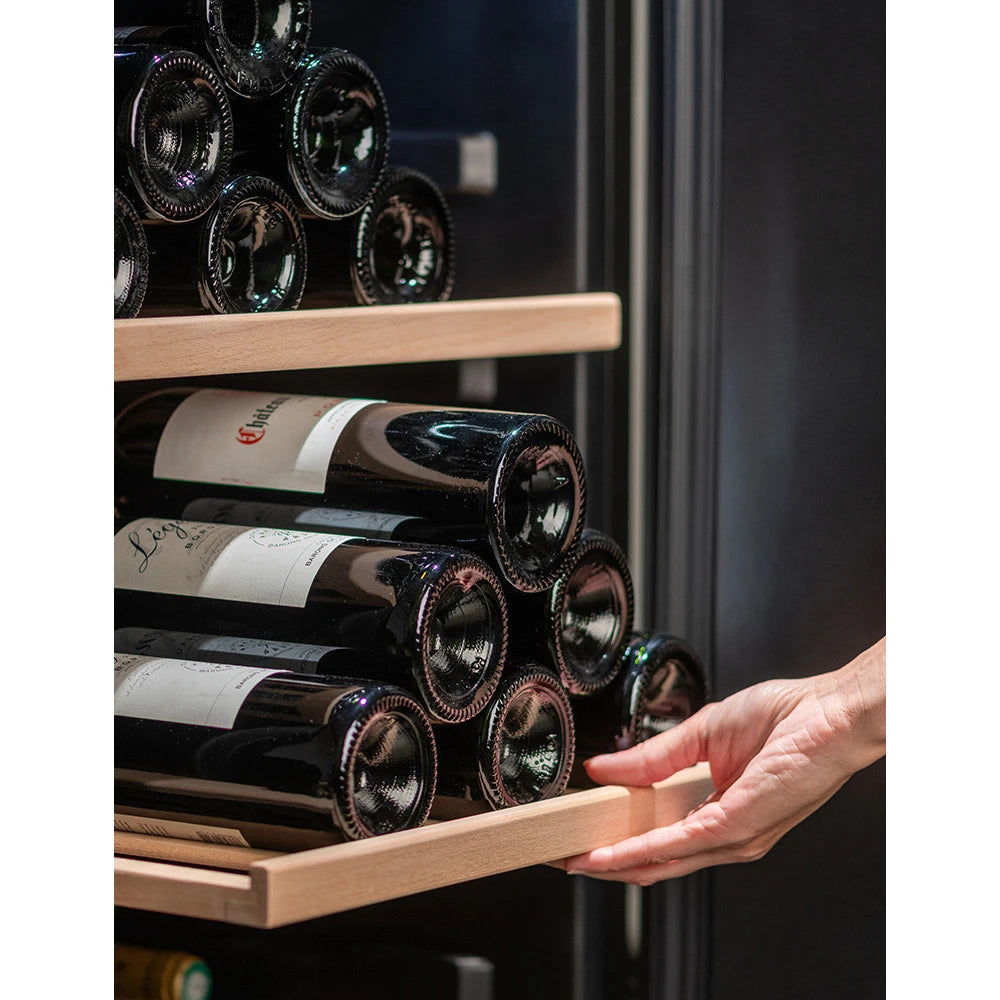 Primer plano de un estante deslizante de madera con varias botellas de vino, siendo sujetado por una mano dentro de la vinoteca La Sommelière CTPNE120E.
