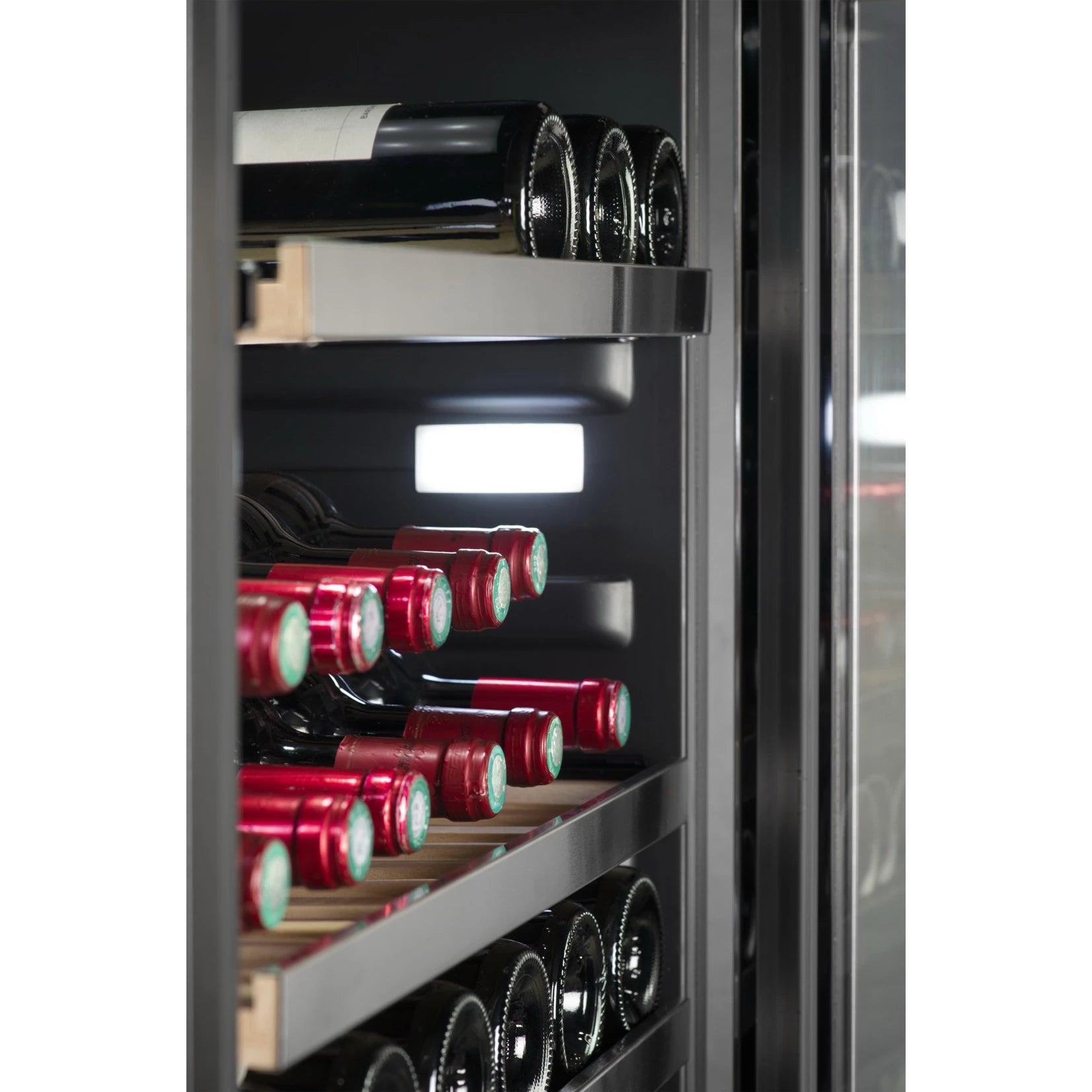 Vista lateral en primer plano del interior de la vinoteca La Sommelière MT150DZ, mostrando estantes con botellas de vino tinto colocadas horizontalmente, iluminación LED blanca en la parte trasera y estructura de rieles metálicos con guías de madera.