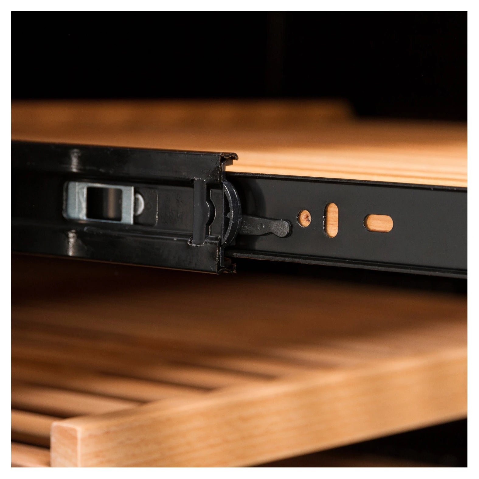 Primer plano del riel metálico deslizante de una bandeja de madera para vinoteca, mostrando el mecanismo de guía lateral en color negro.