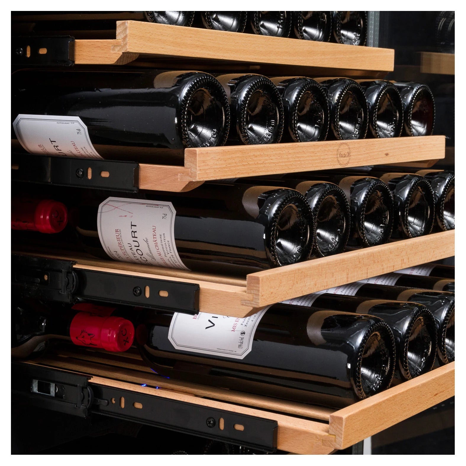 Primer plano de bandejas de madera deslizantes en una vinoteca, con varias botellas de vino colocadas en posición horizontal y rieles metálicos laterales visibles.