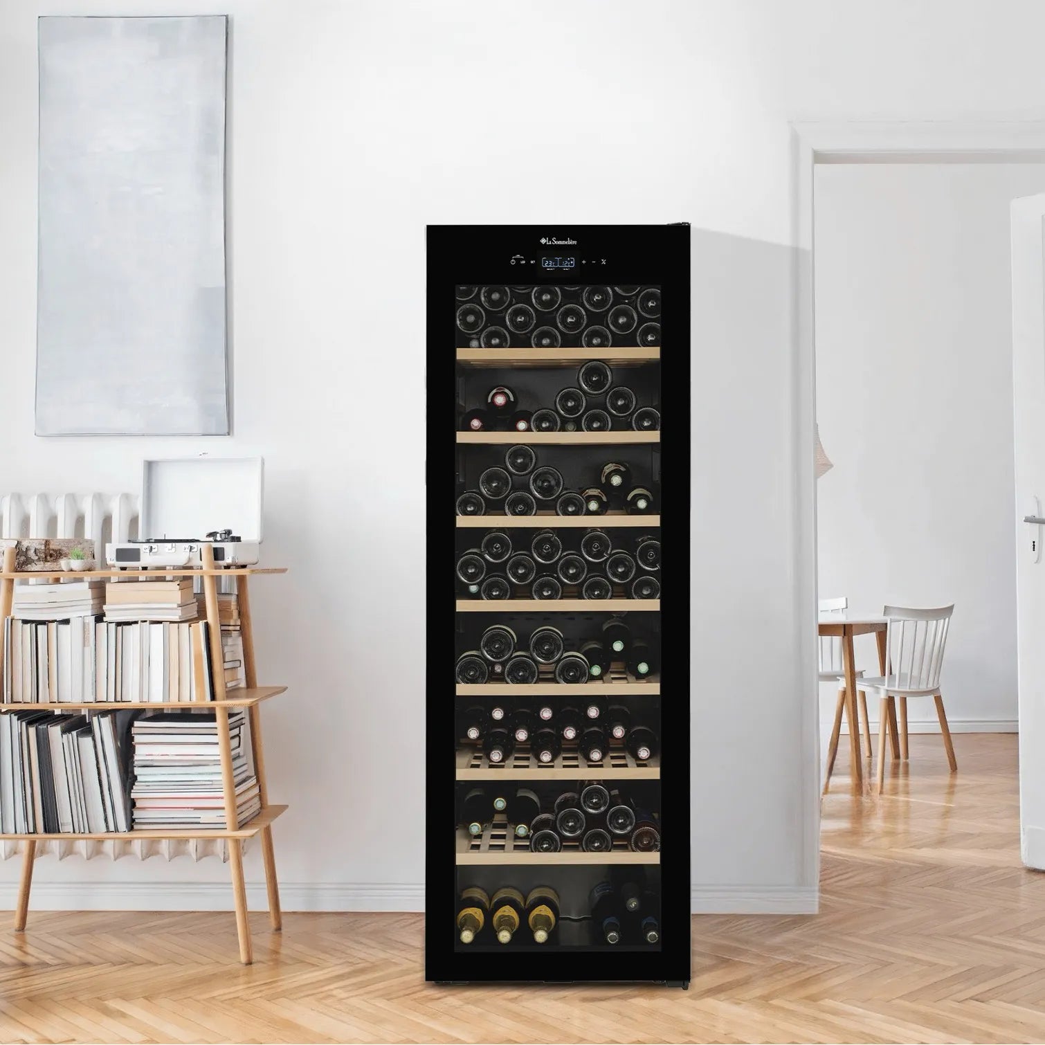 Vinoteca La Sommelière CLASSIC185 ubicada en una sala luminosa de estilo escandinavo, rodeada de muebles de madera clara; se observa completamente cerrada y llena de botellas organizadas.