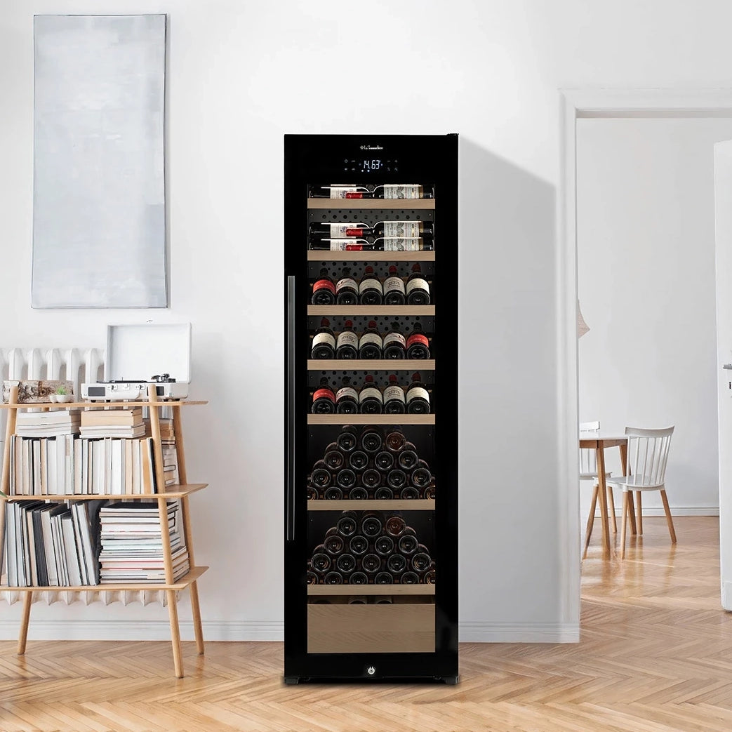 Vinoteca La Sommelière VIP205 EDITION llena de botellas en un salón luminoso junto a una estantería