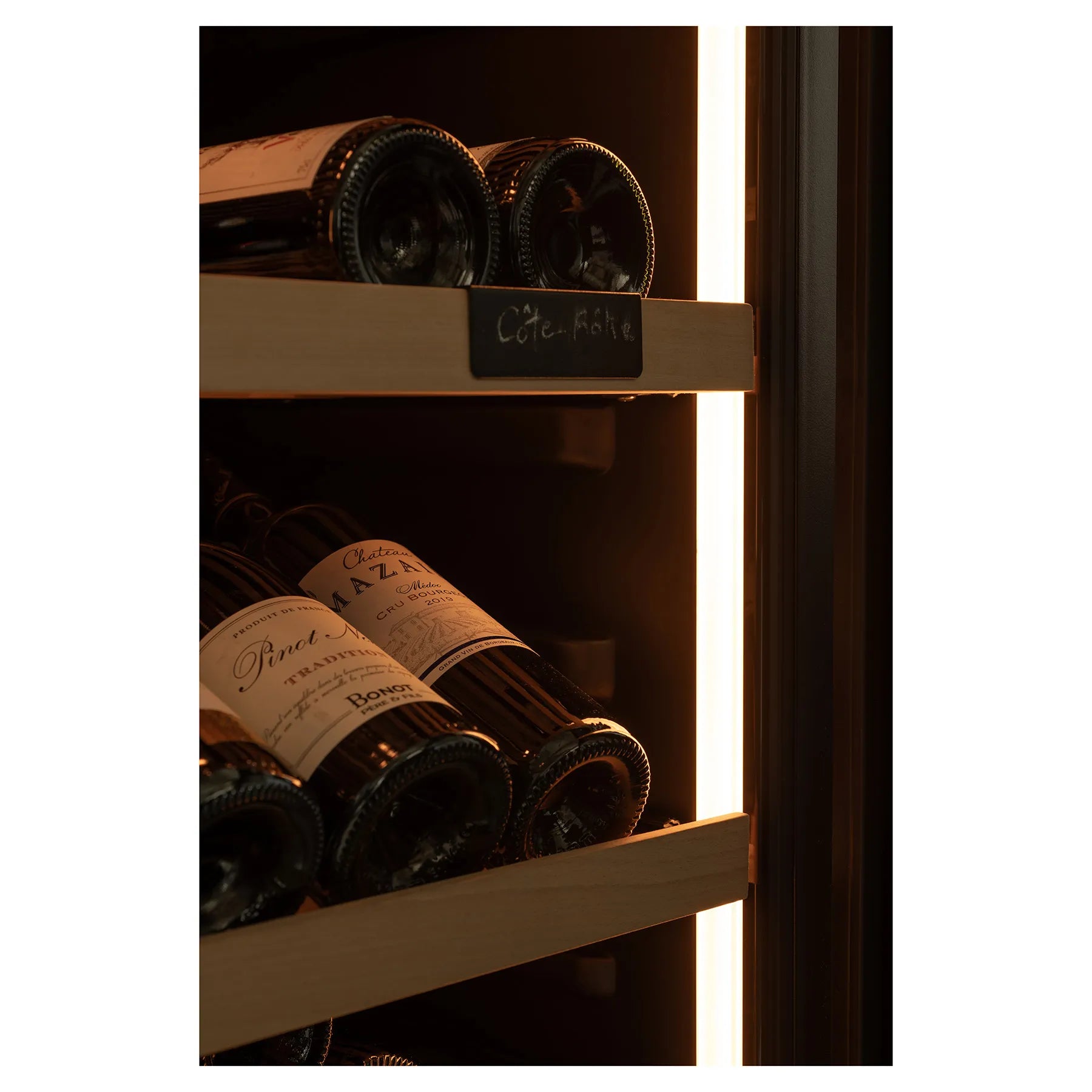 Primer plano de botellas de vino en estante de madera con etiqueta “Côte-Rôtie” y luz cálida en el interior de la vinoteca.