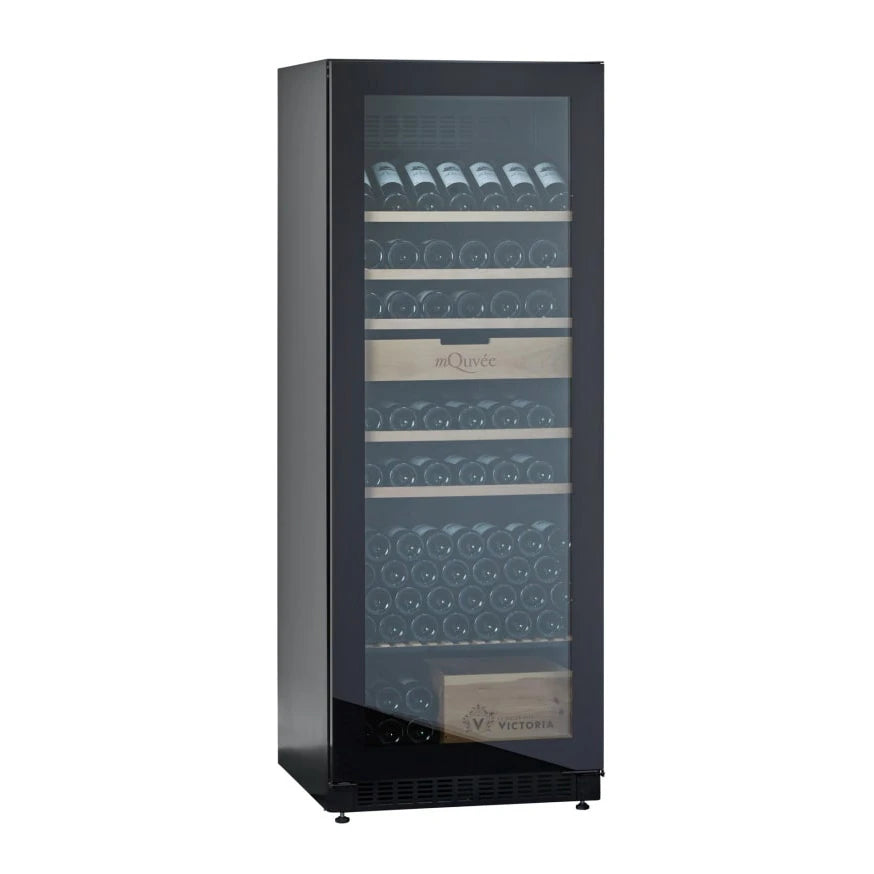 Vista lateral en ángulo de la vinoteca mQuvée VELVET 220 Premium Package con la puerta cerrada, mostrando a través del vidrio tintado varias botellas de vino organizadas en estantes de madera y una caja de madera con el logotipo "VICTORIA" en la parte inferior.