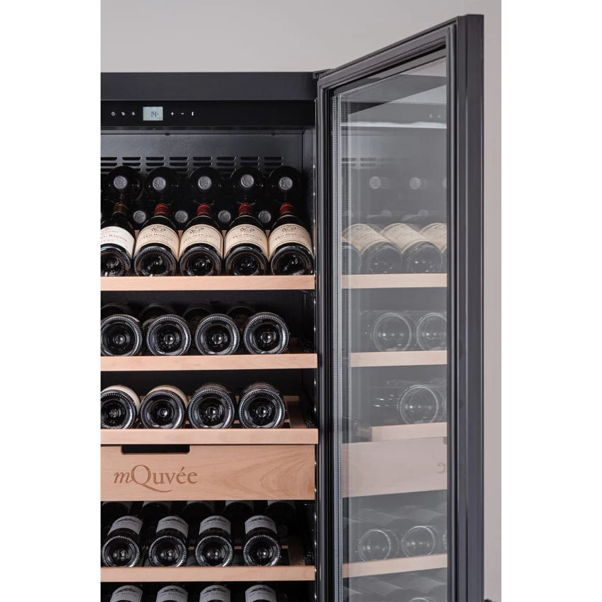 Detalle en primer plano del interior de la vinoteca mQuvée VELVET 220 Premium Package con la puerta de vidrio abierta, mostrando botellas de vino organizadas horizontalmente en estantes de madera y un cajón central grabado con el logo de mQuvée.