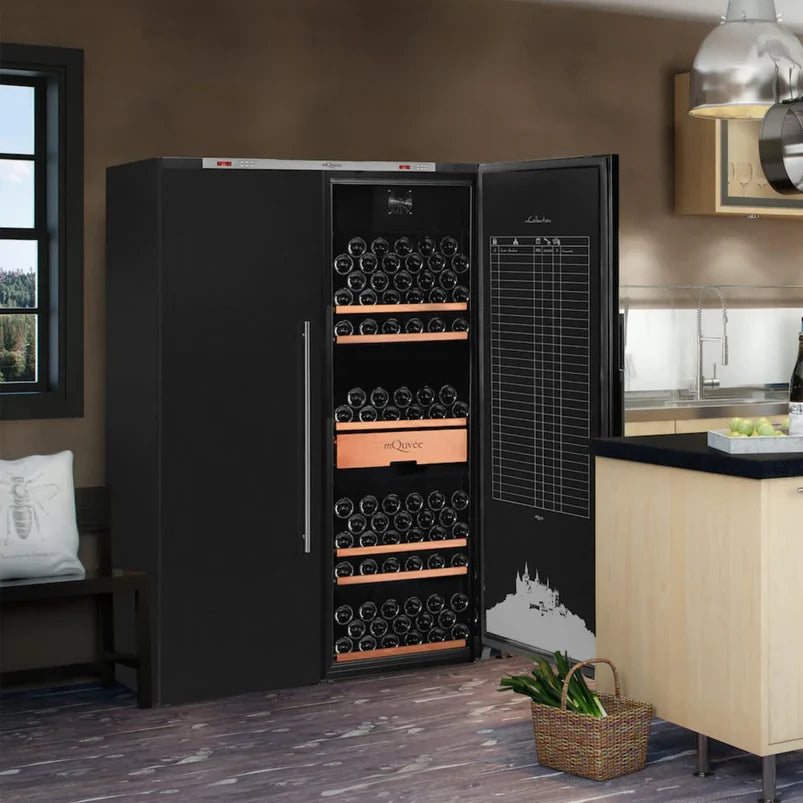 Cocina moderna con una vinoteca mQuvée WineStore 1200 de doble zona a la izquierda, con capacidad para 474 botellas, integrada junto a una isla central de madera clara y estanterías abiertas con utensilios y plantas decorativas.