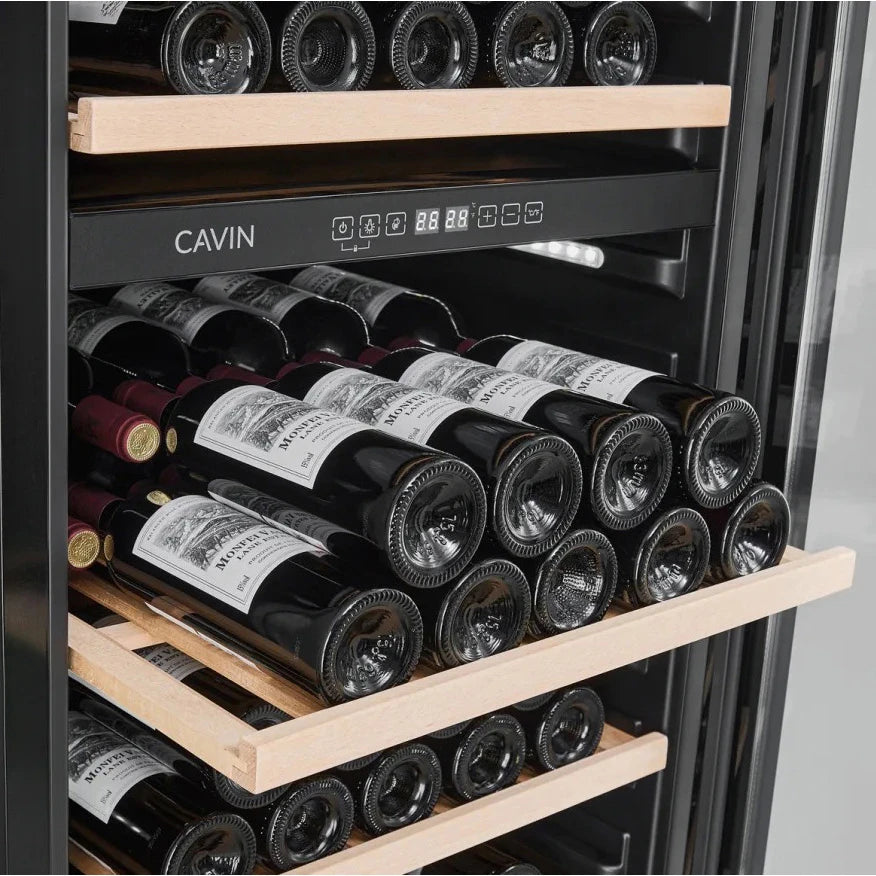 Detalle de estantes de madera con botellas de vino tinto en una vinoteca Cavin Arctic Collection, con la marca y el panel de control digital visibles sobre los estantes.