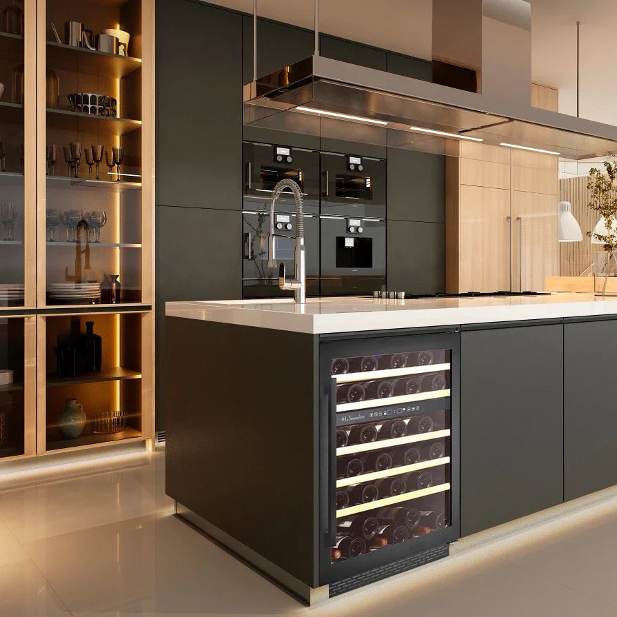 Imagen de cocina de diseño con vinoteca mediana integrada en la isla, rodeada de muebles oscuros, estanterías iluminadas y grifería moderna.